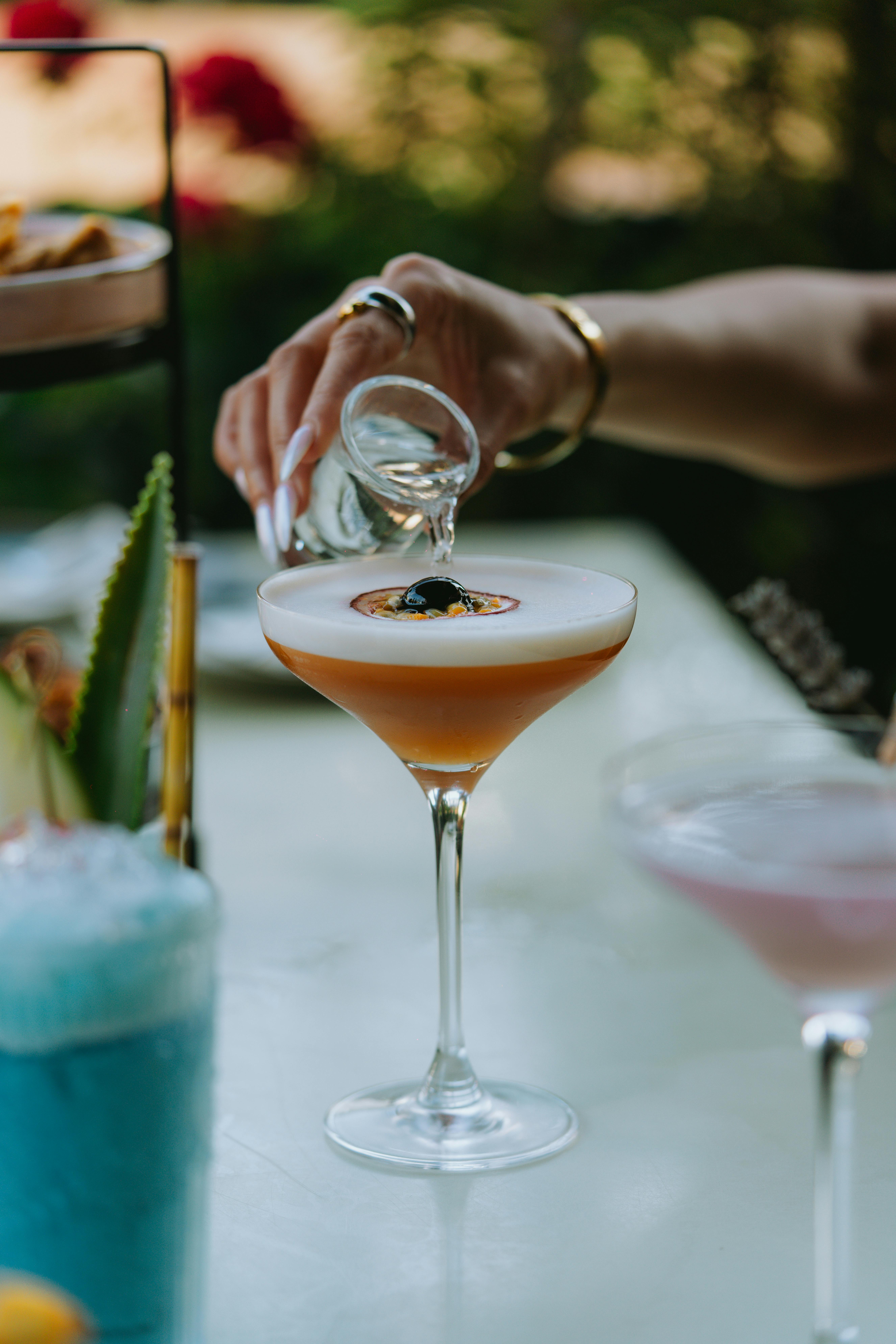 Detailed shot of liquor being poured into a cocktail with garnish.